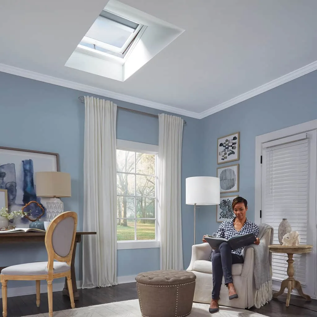 Natural light from a skylight over a woman reading in a bedroom